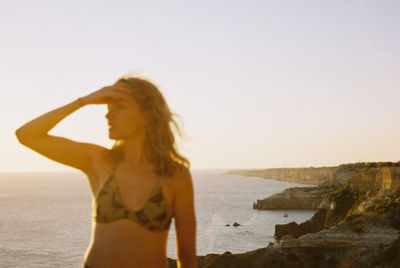 Rear view of woman standing at beach against sky