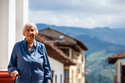 Portrait of young woman standing against building