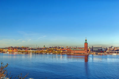 View of buildings by sea against blue sky