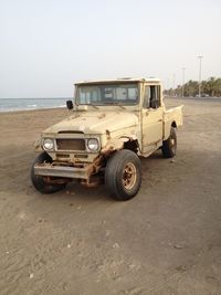 Vintage 4x4 pickup on beach against clear blue sky