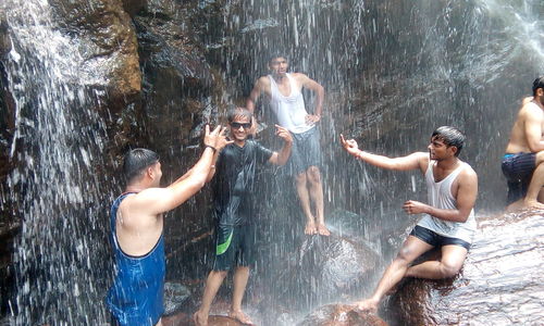 Friends enjoying waterfall at rock formations