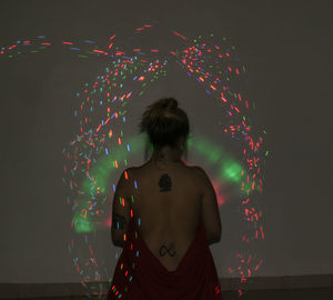 Rear view of woman standing against illuminated lights at night