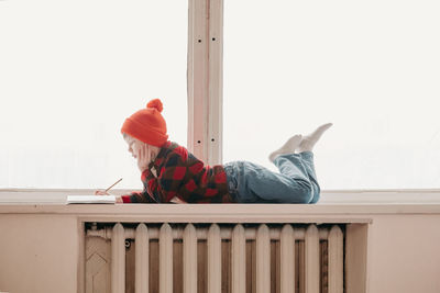 The boy does homework on the windowsill. wide windows and a long window sill. free learning at home. 