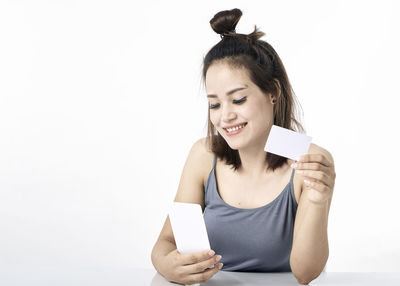 Portrait of a smiling young woman using phone against white background