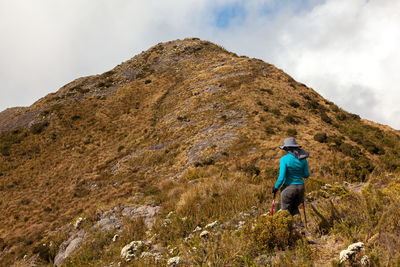 Rear view of man standing on mountain against sky