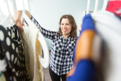 Portrait of a smiling young woman standing against wall