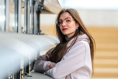 Portrait of confident young woman standing by built structure