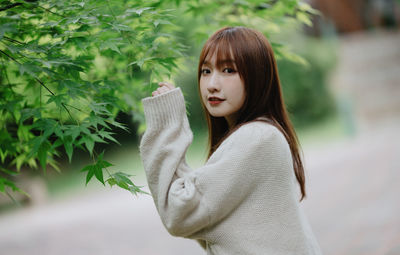 Portrait of young woman standing against plants