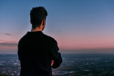 Rear view of man standing against sky during sunset