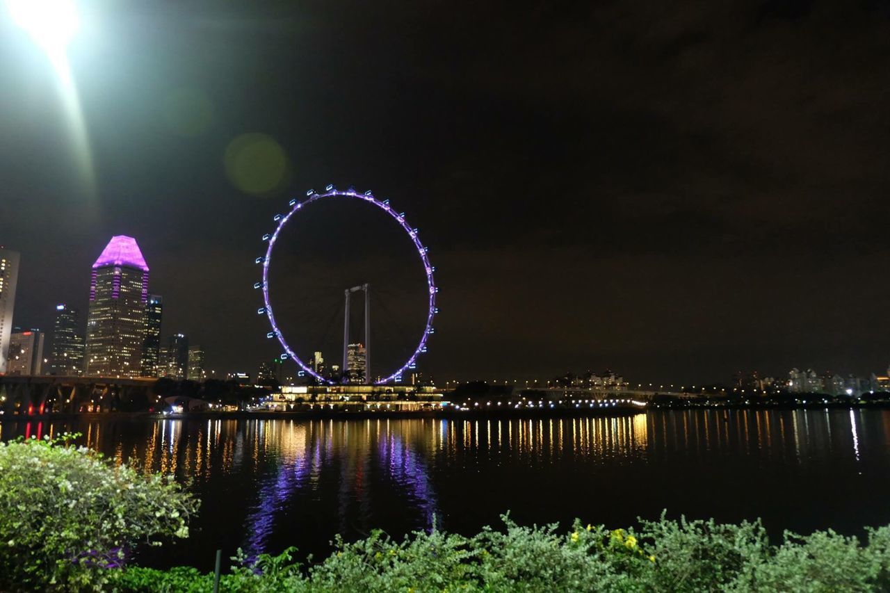 ILLUMINATED FERRIS WHEEL IN FRONT OF BUILDING