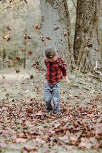 Boy playing with autumn leaves at forest