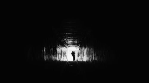 Rear view of silhouette man walking in tunnel
