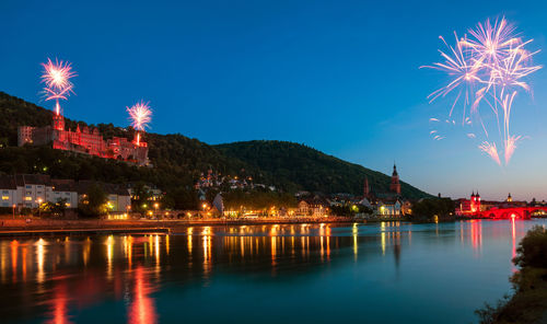Firework display over lake in town at dusk