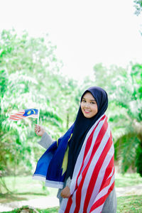 Muslim woman happy holding a malaysian flag. malaysia independence day.