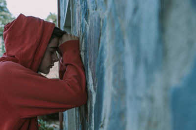 Portrait of young man with hood leaning on the wall
