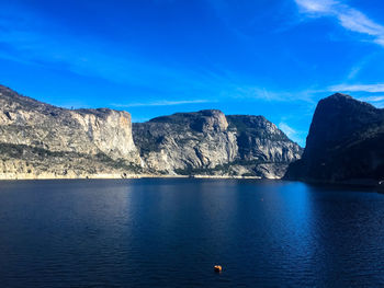 Scenic view of sea and mountains against blue sky