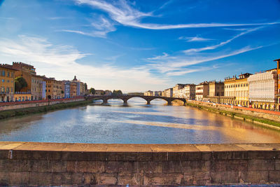 Arch bridge over river against buildings in city