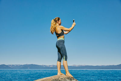 Young woman taking a picture of lake tahoe.