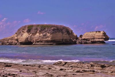 Rock formation on beach against sky