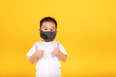 Portrait of boy standing against yellow background