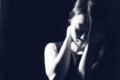 Close-up portrait of young woman against black background