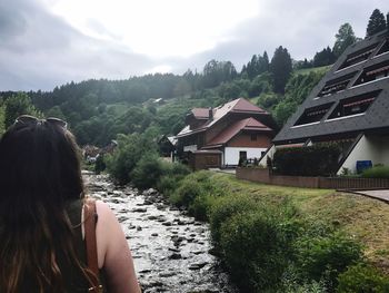 Rear view of woman by houses against sky