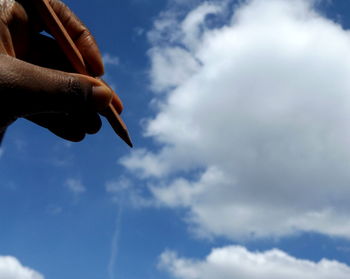 Low angle view of hand against sky