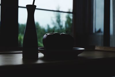 Close-up of silhouette apple on table against window at home