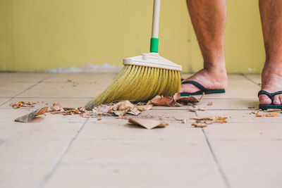 Low section of man cleaning floor with broom