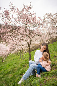 Side view of woman sitting on grassy field