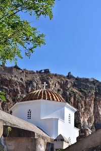 Built structure by trees against clear blue sky