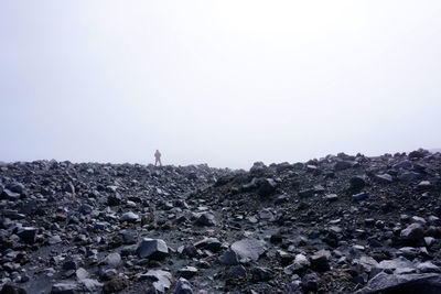 Man standing on rocks against clear sky
