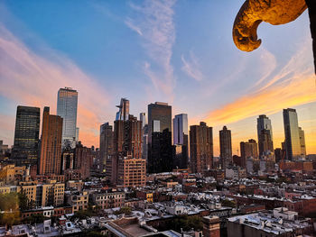 Modern buildings in city against sky during sunset