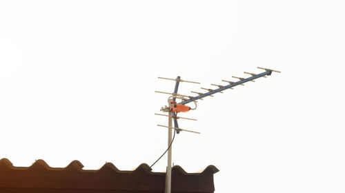 Low angle view of weather vane on roof against clear sky