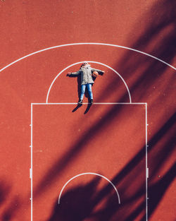 High angle view of woman lying on basketball court