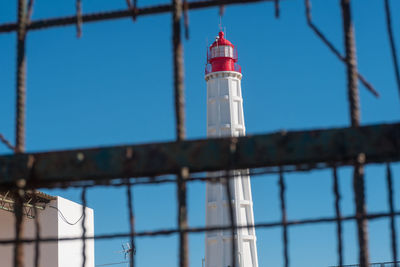 Low angle view of lighthouse against building against clear sky