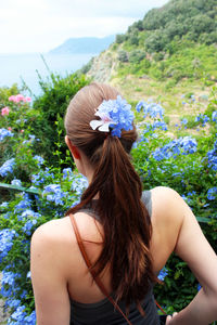 Rear view of woman with flowers in hair standing outdoors
