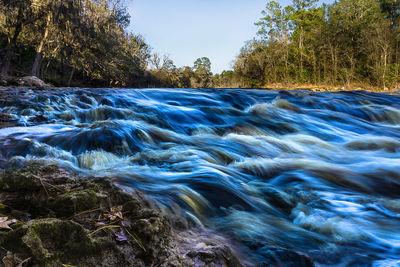 Scenic view of waterfall in forest against clear sky