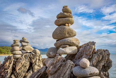 Stack of pebbles on rock against sky