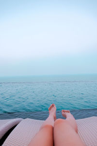 Low section of woman relaxing against sea