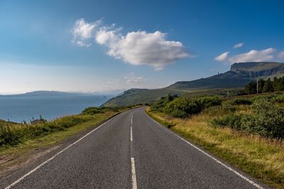 Road amidst green landscape against sky