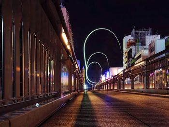 Illuminated light trails on road amidst buildings in city at night