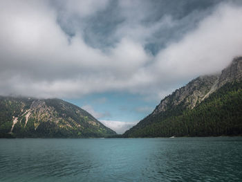 Scenic view of lake by mountains against sky