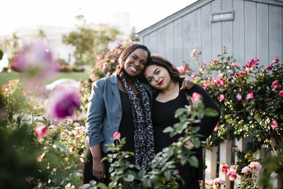 Portrait of happy sisters standing amidst plants at park