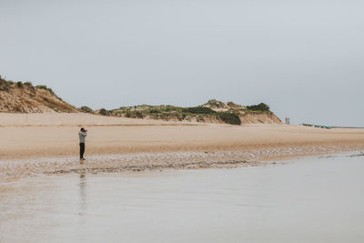 Man standing at beach against clear sky