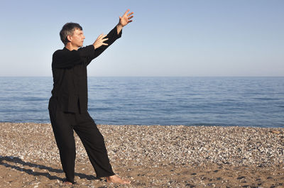 Mature man practicing tai chi on shore at beach