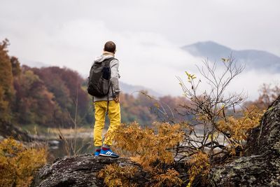 Rear view of man climbing on mountain against sky