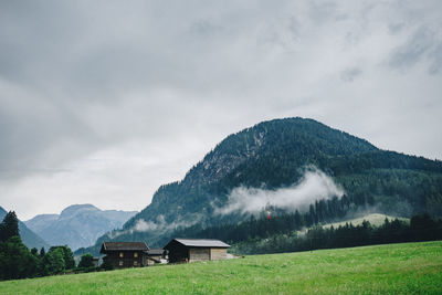 House on field by mountains against sky