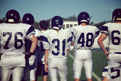 Rear view of female american football players standing on playing field