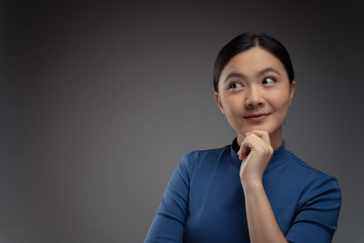 Portrait of a smiling young woman over black background